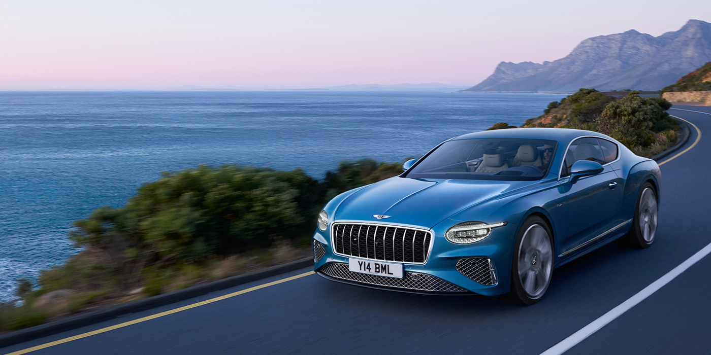 Bentley Knokke New Bentley Continental GT Azure coupe in Light Windsor blue paint with 22 inch Azure wheels and chrome grill, driving dynamically by the sea