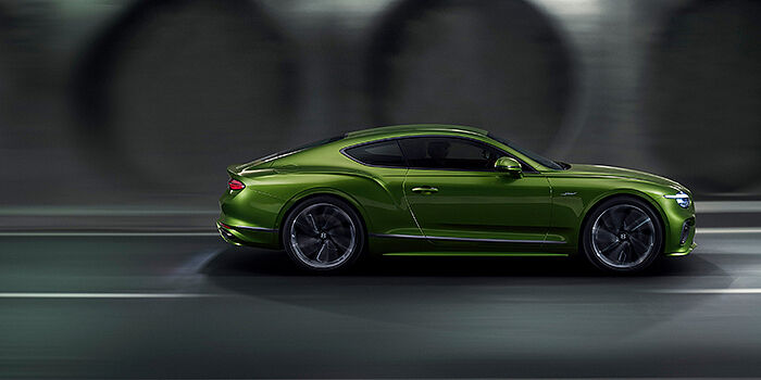  Bentley Knokke Bentley Continental GT coupe in Tourmaline Green paint driving in profile on a dark road