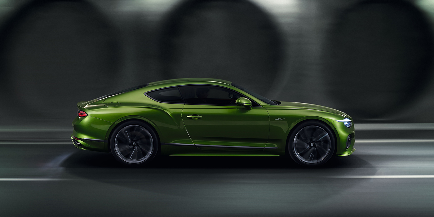Bentley Knokke Bentley Continental GT coupe in Tourmaline Green paint driving in profile on a dark road